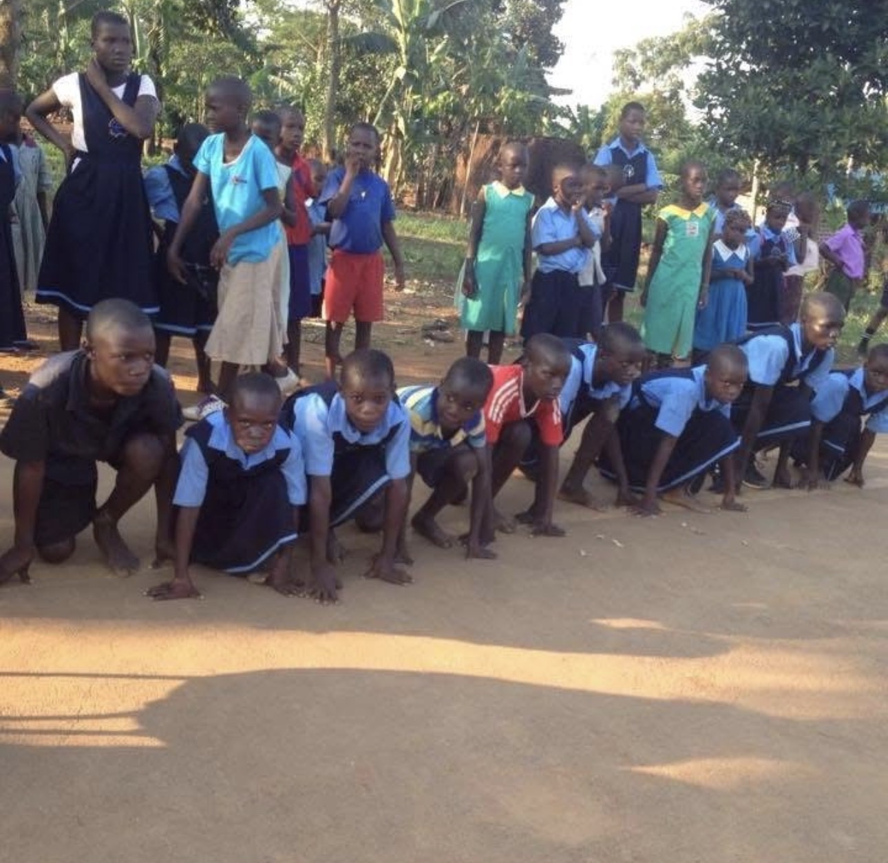 Primary students lined up on the dirt path