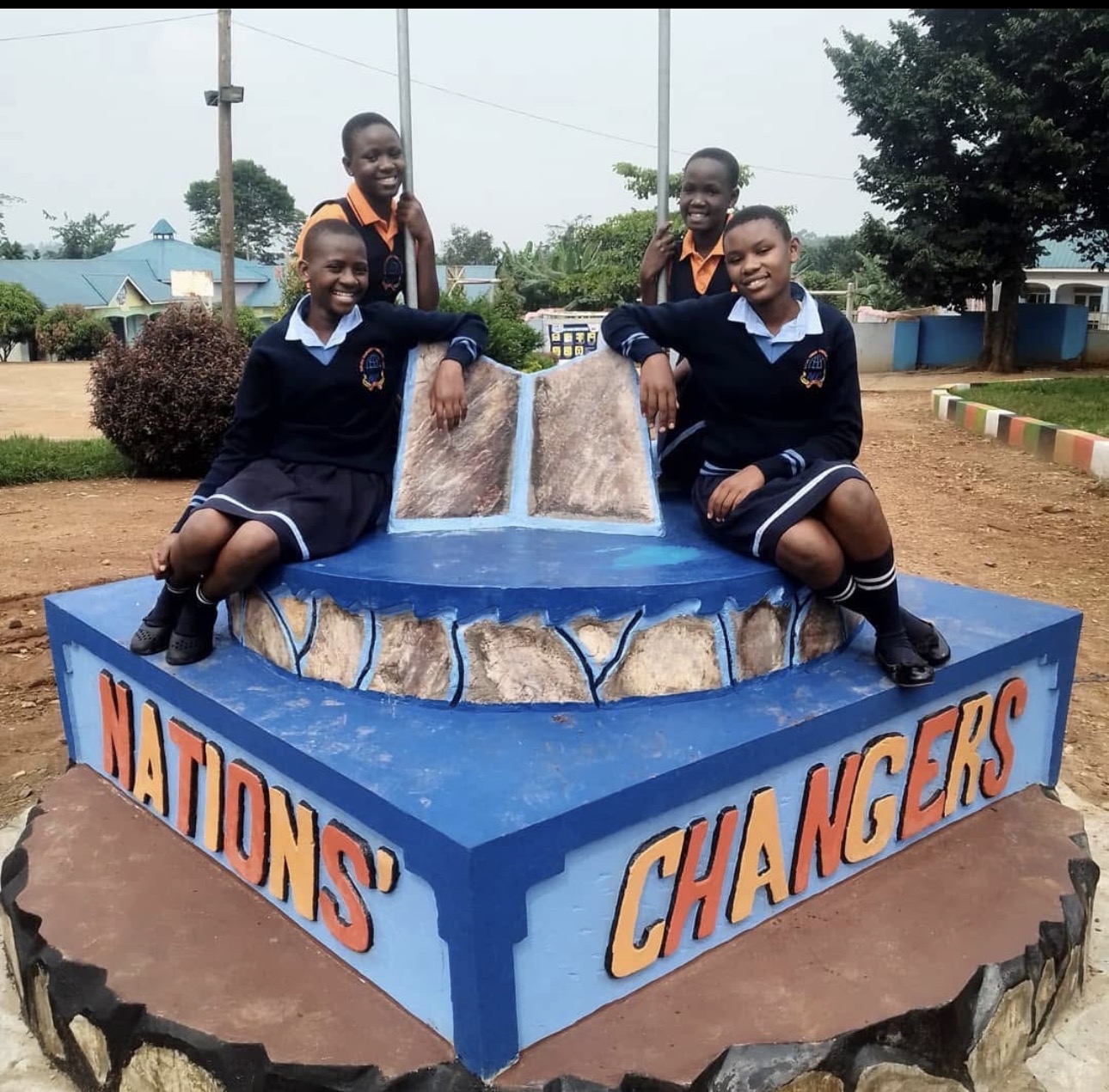 Four Nations' Changers students in navy uniforms by the school monument